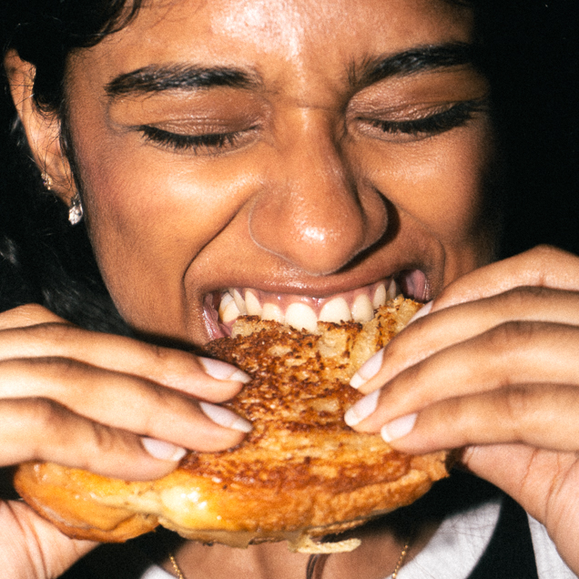 A close-up shot of a Window customer biting into a patty melt.